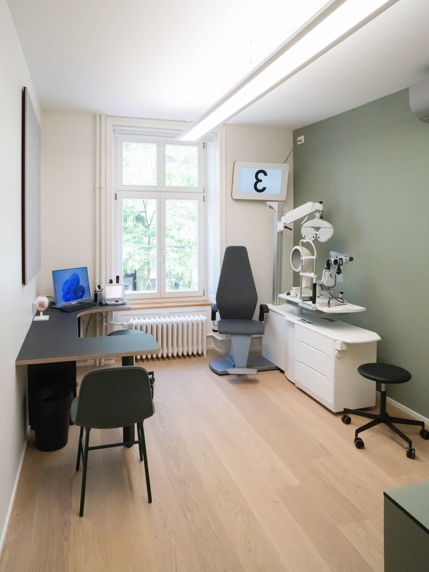 Ein Behandlungszimmer eines Optikers mit einem Beratungstisch und Sehtest-Werkzeug
